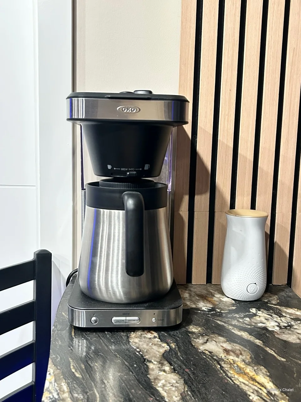 Coffee maker beside a white canister and timber wall slats