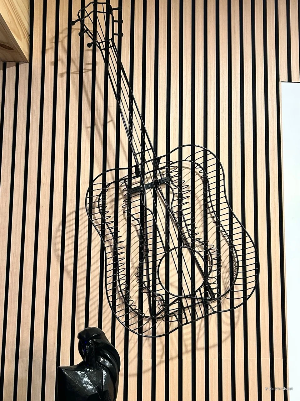 Musical metal artwork mounted on vertical timber slats