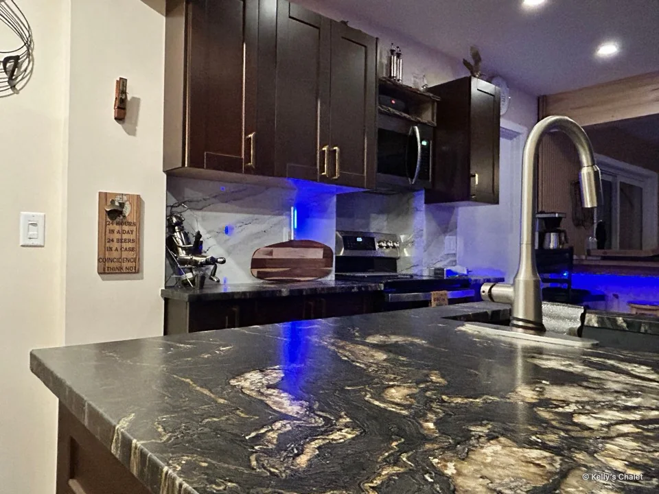 Patterned kitchen countertop and tall tap with dark cabinetry