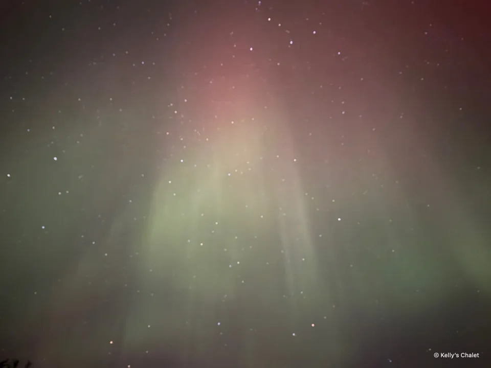 Soft pink and green aurora glow in the Grand Beach area sky, photographed away from Kelly’s Chalet