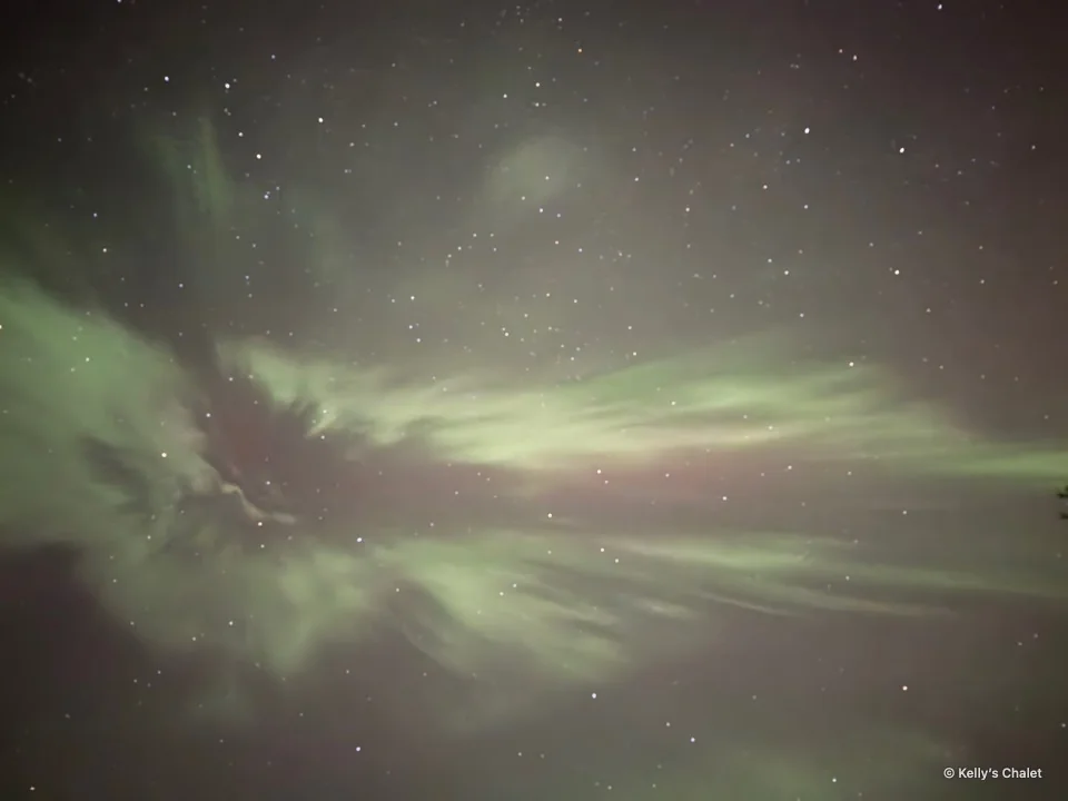 Sweeping green aurora formations in the Grand Beach area night sky, photographed away from Kelly’s Chalet