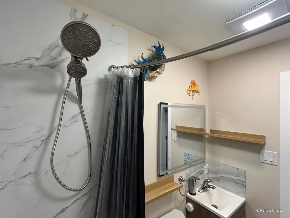 Washroom shower head above the bath with a mirror and vanity beyond