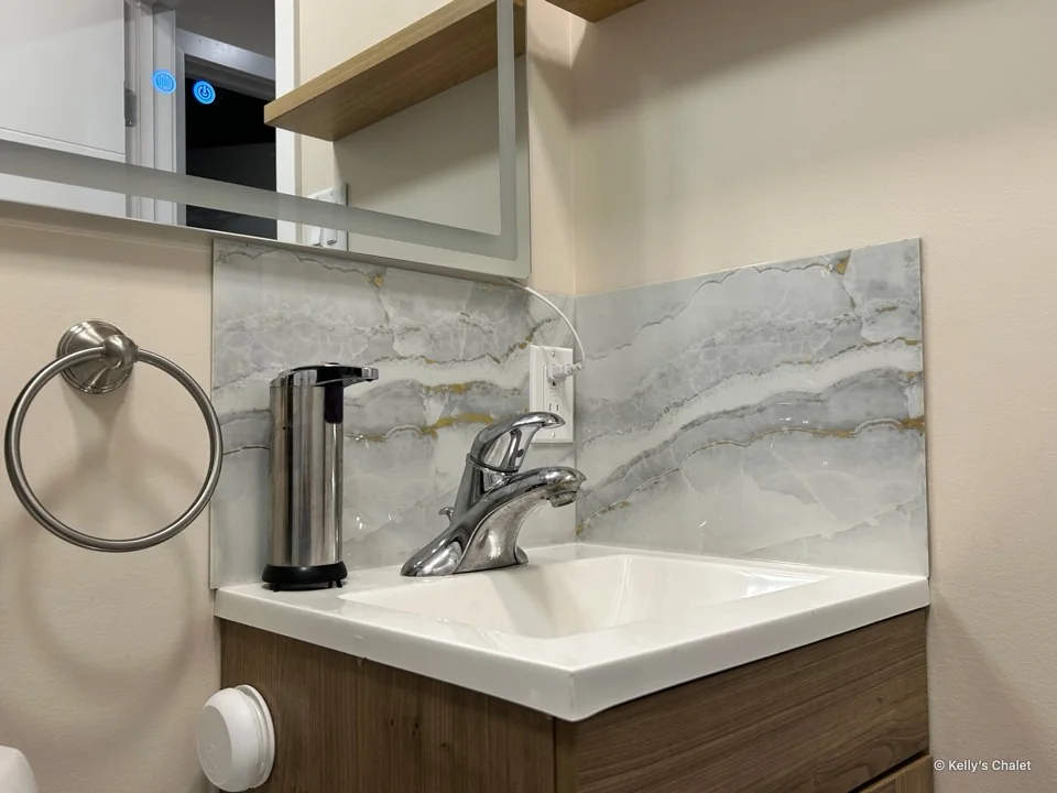Washroom sink and tap with patterned backsplash and mirror